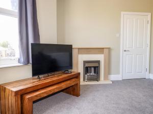 TV de pantalla plana sobre una mesa de madera en Pendeen en Par