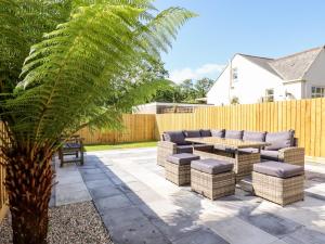 a patio with chairs and a table and a palm tree at Pendeen in Par