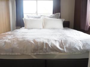 a white bed with white pillows and a window at Harbour Inn & Suites - Vacation STAY 8829 in Niigata