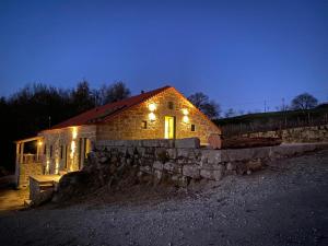 une maison en pierre éclairée la nuit dans l'établissement Quinta Casa do Retiro, à Penalva do Castelo