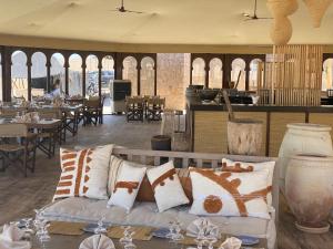 uma sala de estar com um sofá, mesas e cadeiras em Le Bédouin agafay em Marrakech