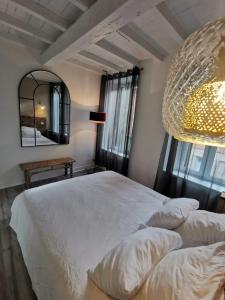 a bedroom with a white bed and a large mirror at La Caponnière in Carcassonne