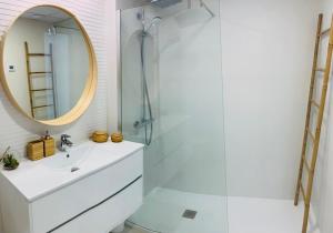ein Bad mit einem Waschbecken, einem Spiegel und einer Dusche in der Unterkunft Villa Jasmin in Finestrat