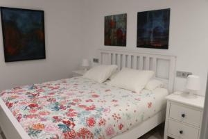 a white bedroom with a bed with a floral comforter at Boutique & Chic in Oviedo