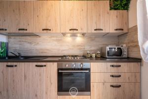 uma cozinha com armários de madeira, um fogão e um micro-ondas em Mary's House - WiFi & Private Parking em Gonnesa