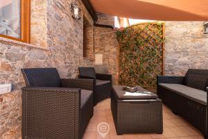 um pátio com cadeiras e mesas de vime e uma parede de pedra em Mary's House - WiFi & Private Parking em Gonnesa