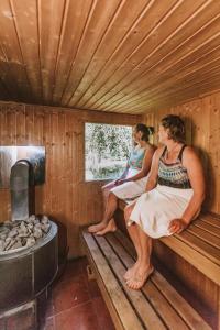 dos mujeres sentadas en un banco en una sauna en River Valley Lodge, en Taihape