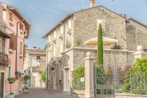 - un bâtiment en pierre avec un parasol dans une rue dans l'établissement Maison Resola - Rooms & Breakfast, à Valeggio sul Mincio