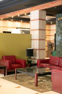 a lobby with red leather couches and a table at Hotel Sercotel Ciudad de Oviedo in Oviedo