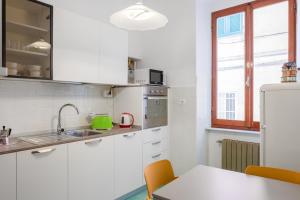 uma cozinha com armários brancos, uma mesa e uma janela em Cadimare Lovely Apartment em La Spezia