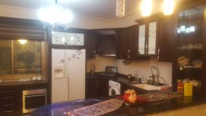 cocina con armarios de madera y nevera blanca en Nablus luxury Residence en Nablus