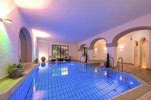- une grande piscine avec des carreaux bleus dans un bâtiment dans l'établissement Hotel Hirsch, à Oberstaufen