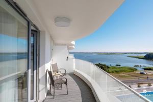 a balcony with two chairs and a view of the water at Jantar Apartamenty - Pearl Apartments Rogowo in Rogowo
