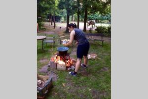 una mujer cocinando sobre un fuego en una olla en Igricz Farmház, en Pócsmegyer