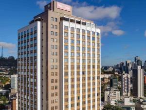 un grand bâtiment avec un panneau d'hôtel en haut dans l'établissement Mercure Belo Horizonte Lourdes, à Belo Horizonte