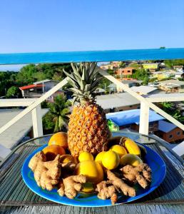 a blue plate with a pineapple and other fruits on a table at onelovecottagetobago upstairs apartment in Scarborough