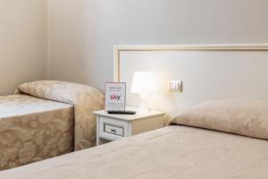 um quarto com duas camas e uma mesa com uma placa em Hotel Astoria em Cremona