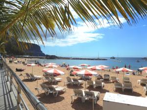 ein Strand mit Stühlen und Sonnenschirmen und das Meer in der Unterkunft Puerto De Mogan Harbour 371 by El Sirocco in Puerto de Mogán