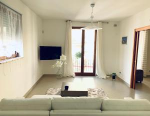 a white living room with a couch and a tv at Dimora Anvi - Relax Fronte Mare in Polignano a Mare