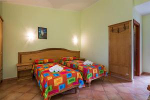 1 dormitorio con 2 camas y sábanas coloridas en Hotel Is Murtas, en Jerzu