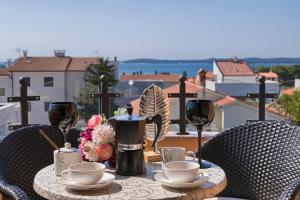 einen Tisch mit Weingläsern und Blumen auf dem Balkon in der Unterkunft Villa Mihaela in Fažana