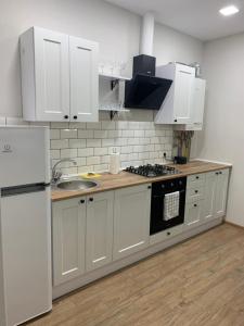 a kitchen with white cabinets and a sink and a refrigerator at 024 Loft - Апартаменты ЖК «Софиевская Слободка» in Vyshneve