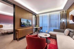 a hotel room with a couch and a bed at Novotel Dongguan Songshan in Dongguan