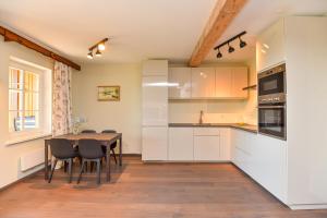 a kitchen with white cabinets and a table and chairs at Anties Namai in Juodkrantė