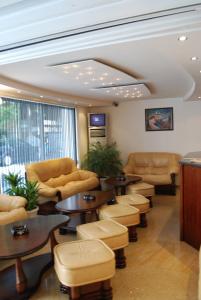 una sala de espera con sofás, mesas y sillas en Italia Hotel, en Nesebar