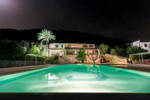 a swimming pool at night with a house in the background at Hotel Is Murtas in Jerzu
