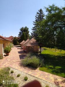 un jardín con una pasarela de ladrillo, árboles y césped en Spengler Apartman, en Harkány