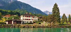 a house on the shore of a lake with mountains at Lake House in Bönigen