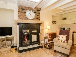 a living room with a fireplace with a clock on the wall at Chapel Cottage in Redcar