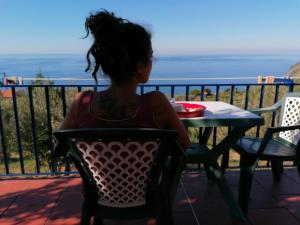 a little girl sitting at a table looking at the ocean at Perla del Levante Hostel in Framura