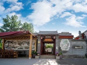 a building with awning and tables and chairs at Dong Li Guest House in Miyun