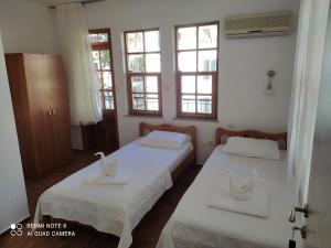 two beds in a room with two windows at meltem pansiyon in Kas