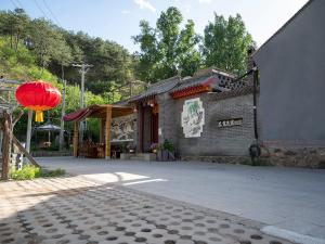 un edificio con una linterna roja delante de él en Dong Li Guest House en Miyun