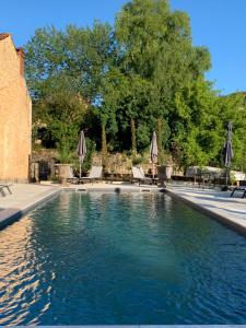 uma piscina com cadeiras e guarda-sóis em Les appartements d artiste de la Villa du 15 - Restaurant La Maison - piscine chauffée em Les Eyzies-de-Tayac