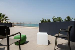 a patio with chairs and a table and the ocean at Hotel Punta Tipa in Trapani