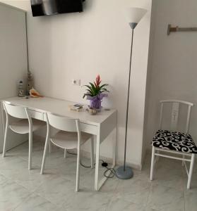 una mesa blanca con sillas y una lámpara en una habitación en B&B Bentu de Mari, en Villasimius