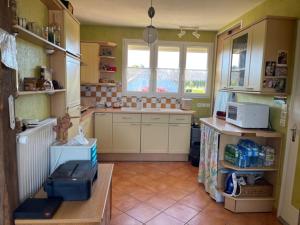 cocina con armarios blancos, fregadero y ventana en Le chasse marée en Offranville