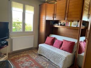 een slaapkamer met een bed met roze kussens erop bij Le chasse marée in Offranville