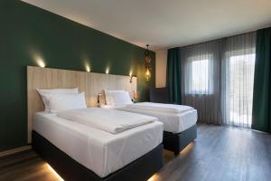 Cette chambre comprend 2 lits et un mur vert. dans l'établissement ACHAT Hotel Reilingen Walldorf, à Reilingen