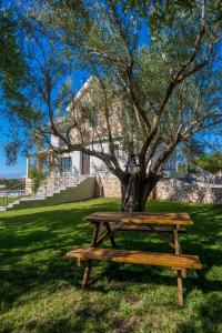 a wooden picnic table next to a tree at Filon Ktima Beachfront Upscale Villa in Karavádhos