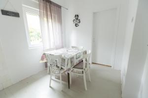 una mesa y sillas blancas en una habitación con ventana en Apartment Room with a view, en Podgora