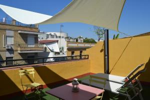 eine Terrasse mit einem Tisch, Stühlen und einem Sonnenschirm in der Unterkunft ALOJAMIENTO EN SEVILLA-TRIANA in Sevilla