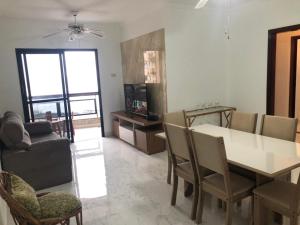 uma sala de estar com uma mesa de jantar e cadeiras em Apartamento solar vitória regia - Frente Mar na Praia Grande