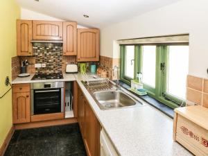 a kitchen with wooden cabinets and a sink at Trewrach Cottage in Newport