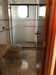 uma casa de banho com um WC e uma cabina de duche em vidro. em Apartamento solar vitória regia - Frente Mar na Praia Grande