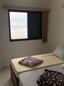 two twin beds in a room with a window at Apartamento solar vitória regia - Frente Mar in Praia Grande